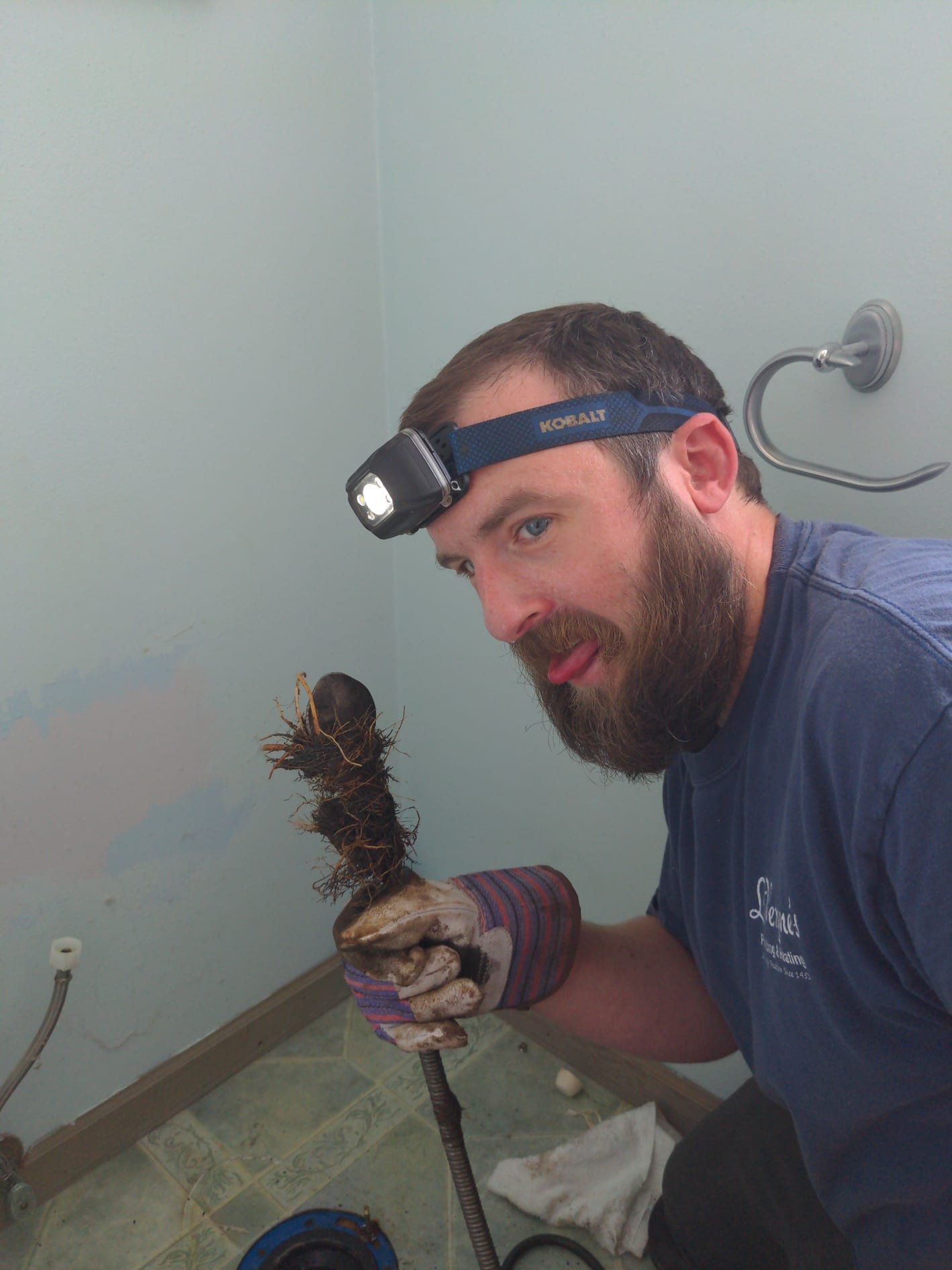 Technician measuring sludge depth in a septic tank during LaVergne's pumping service