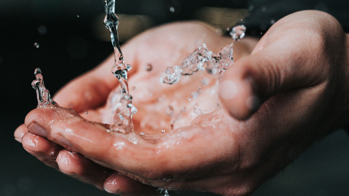 Clean water flowing over hands, the result of whole house filtration treatment